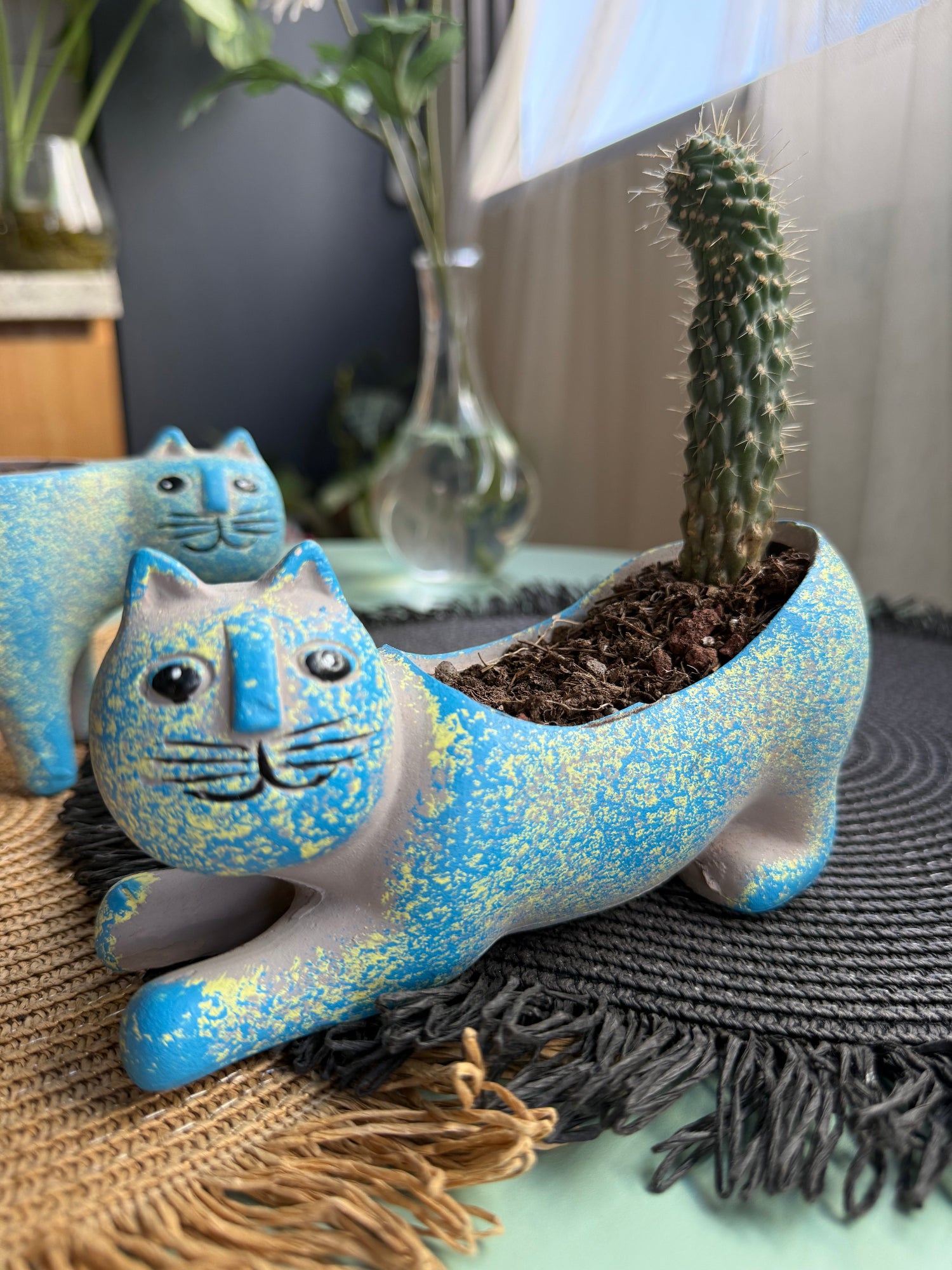 Blue ceramic cat-shaped planter with textured finish, placed among plants and decor.